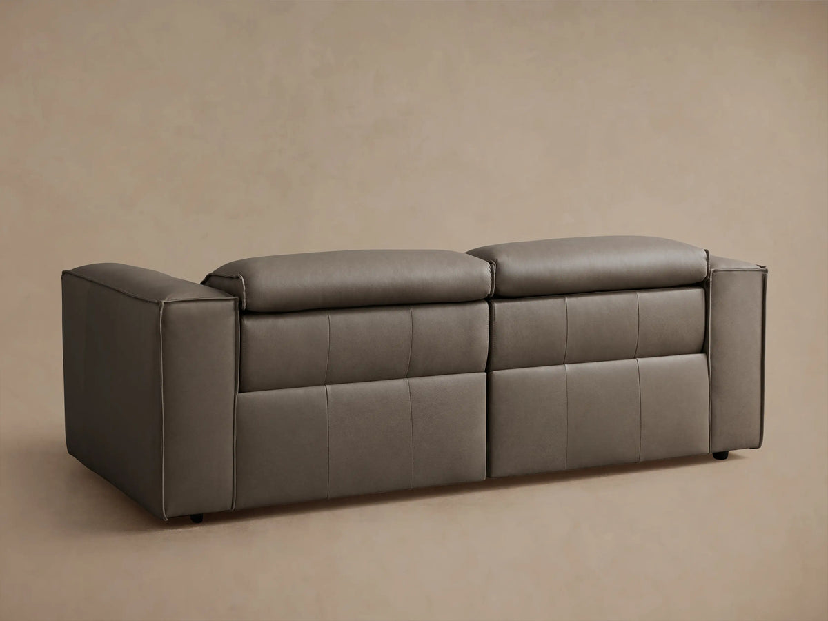 Two-piece motion sofa in brown leather with reclined footrests extended, featuring padded armrests and cushioned backrests.