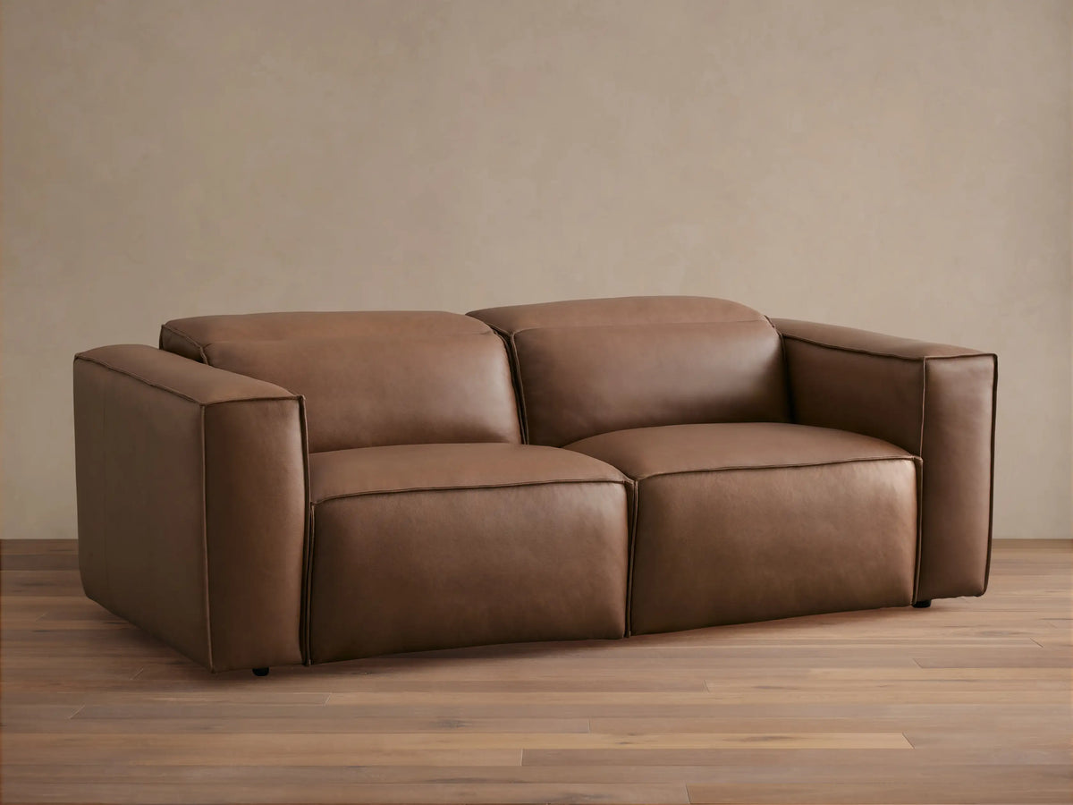 Coburn Leather Two-Piece Motion Sofa in light brown leather with clean lines and plush cushions, featuring a minimalist design.