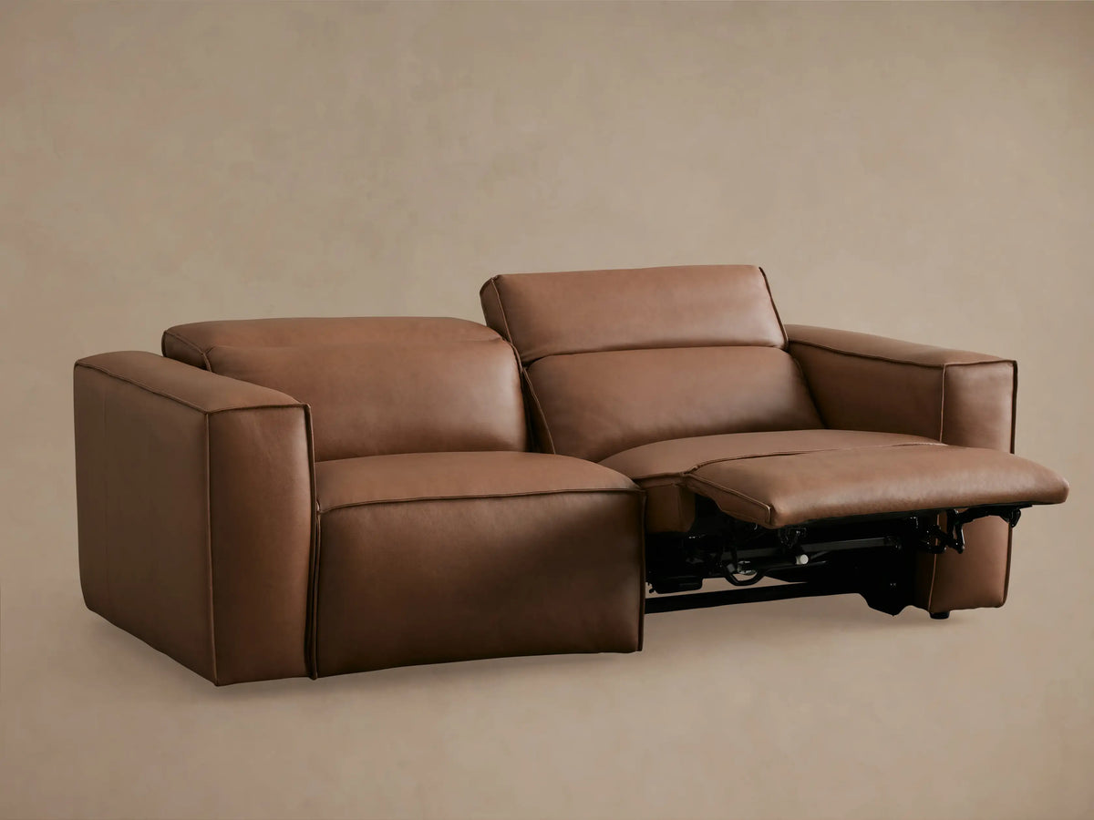 Alt text: Coburn Leather Two-Piece Motion Sofa in brown leather with one seat reclined and footrest extended on the left.