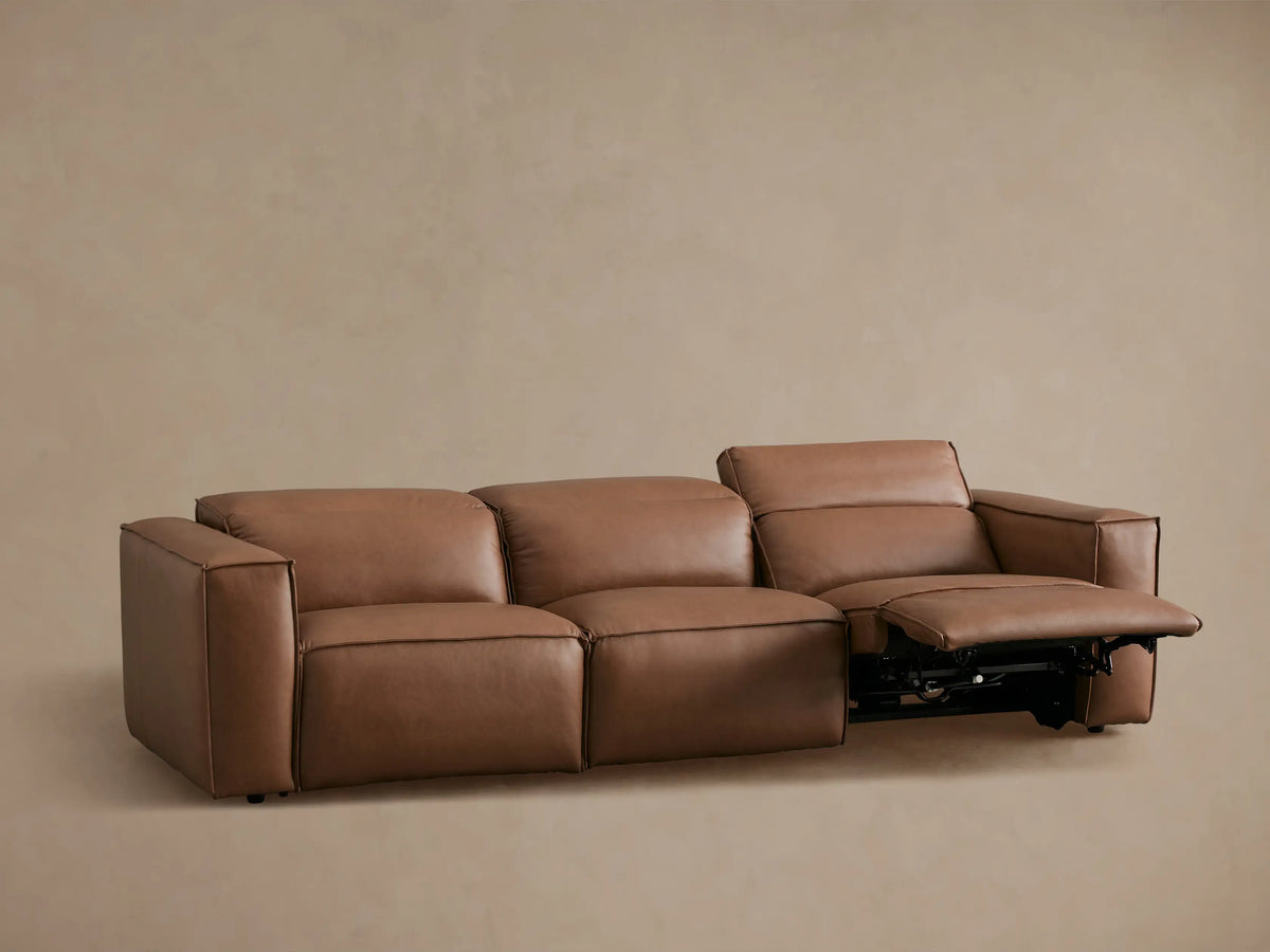 Coburn Leather Three-Piece Motion Sofa in brown leather, viewed from back. Sofa features three connected sections with thick cushions and visible seams.