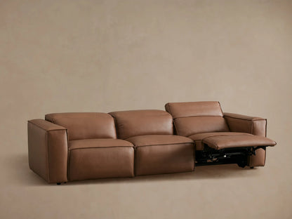 Coburn Leather Three-Piece Motion Sofa in brown leather, viewed from back. Sofa features three connected sections with thick cushions and visible seams.