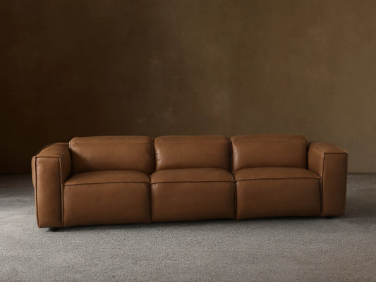 Coburn Leather Three-Piece Motion Sofa in brown leather finish, featuring three recliners with armrests on ends, positioned in a bright room.