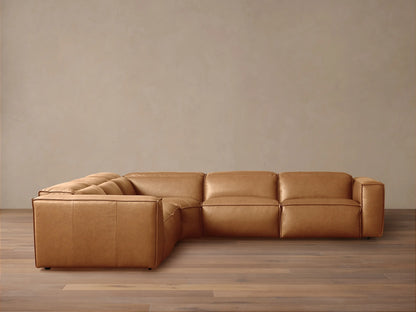 Tan leather Coburn Five-Piece Motion Corner Sectional. L-shaped sofa with plush cushions on wooden floor, beige wall.