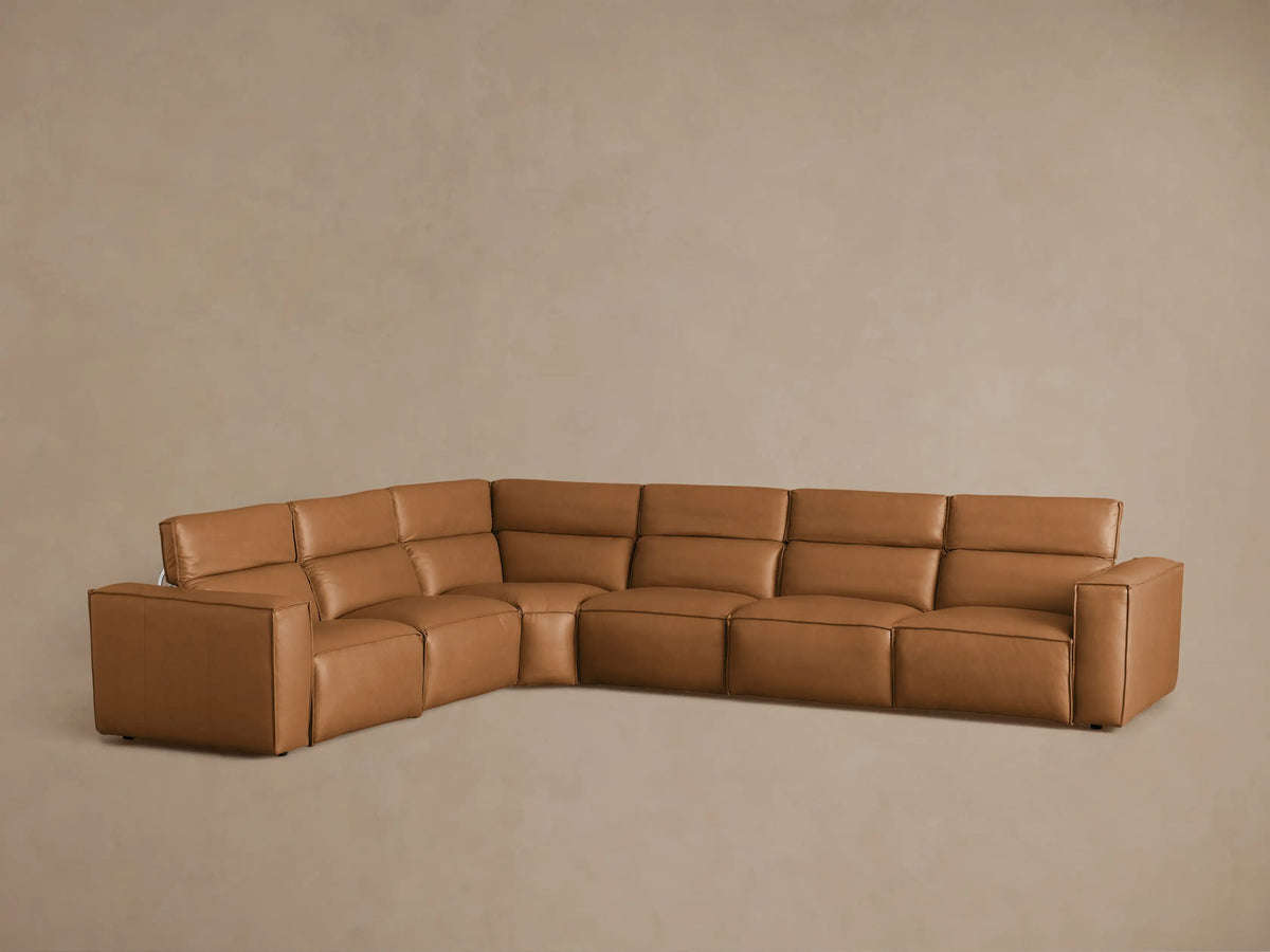 Coburn Leather Six Piece Motion Sectional in a warm brown tone, arranged in an L-shape. Features padded seats and backrests, with visible motion controls.
