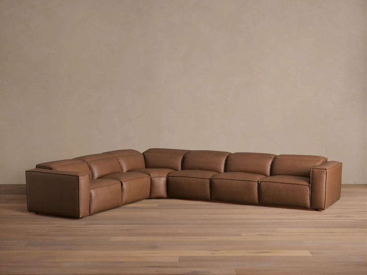 Coburn Leather Six Piece Motion Sectional in brown leather, featuring a left arm recliner, corner section, and four additional seats on a wooden floor.
