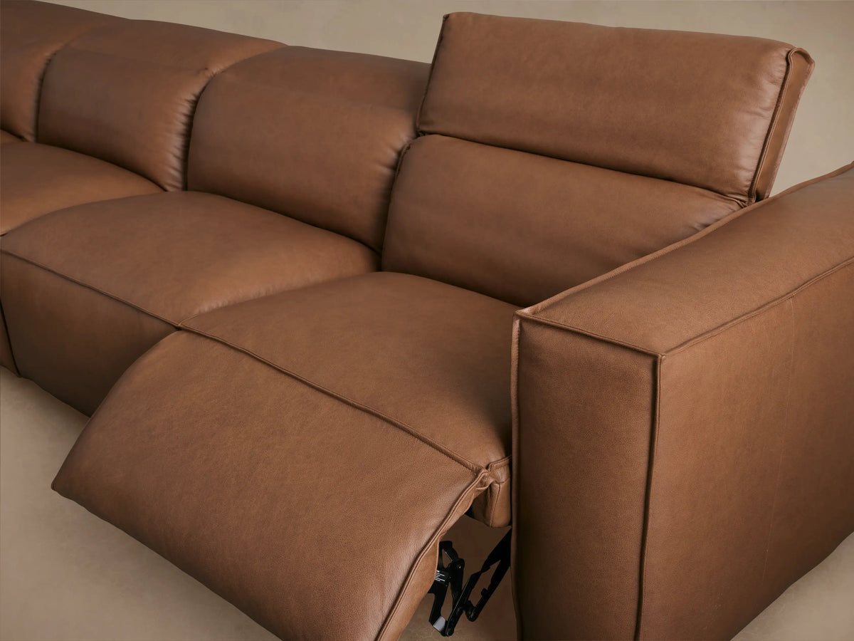 Coburn Leather Six Piece Motion Sectional in brown leather with a modern L-shaped design. Features smooth plush cushions on a wooden floor.