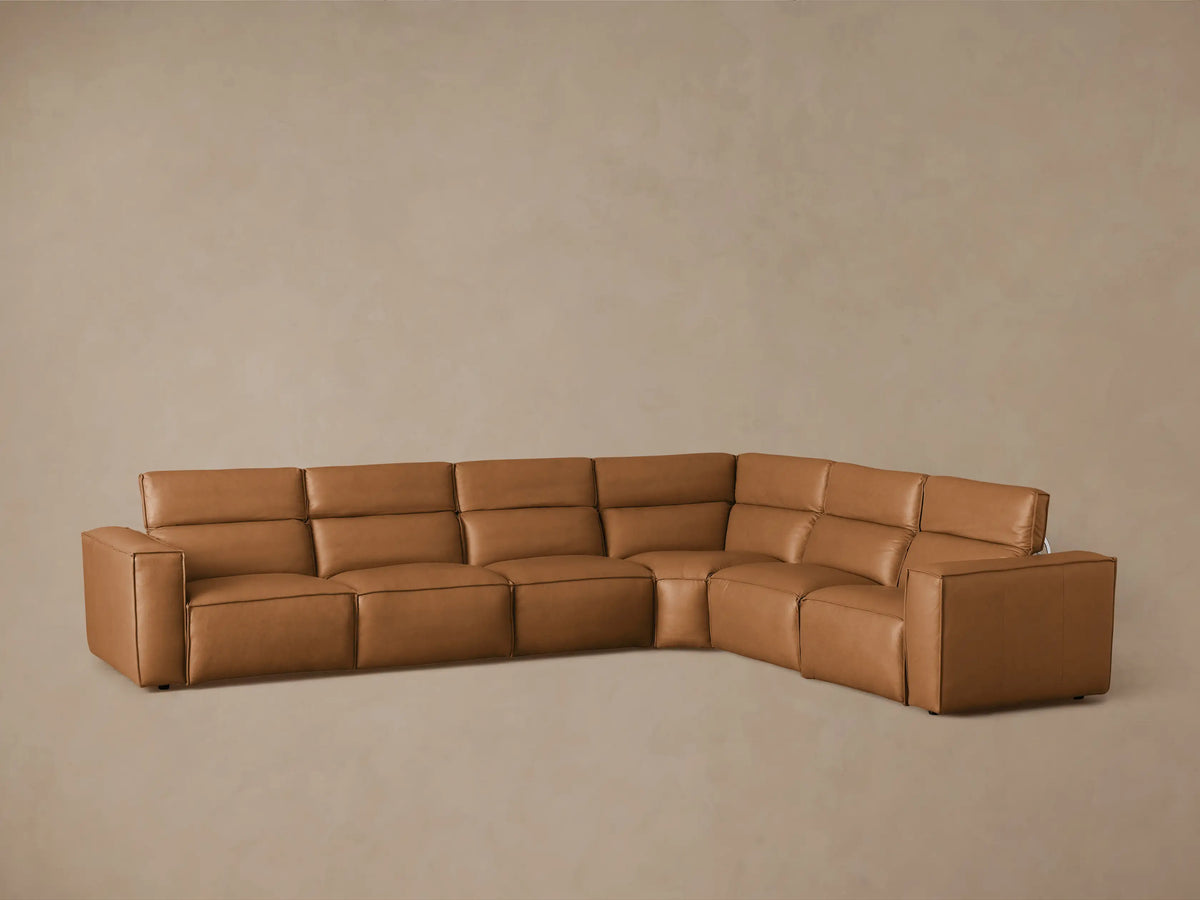 Coburn Leather Six Piece Motion Sectional in caramel brown. Features plush seating with one reclined seat, showing black metal mechanisms.