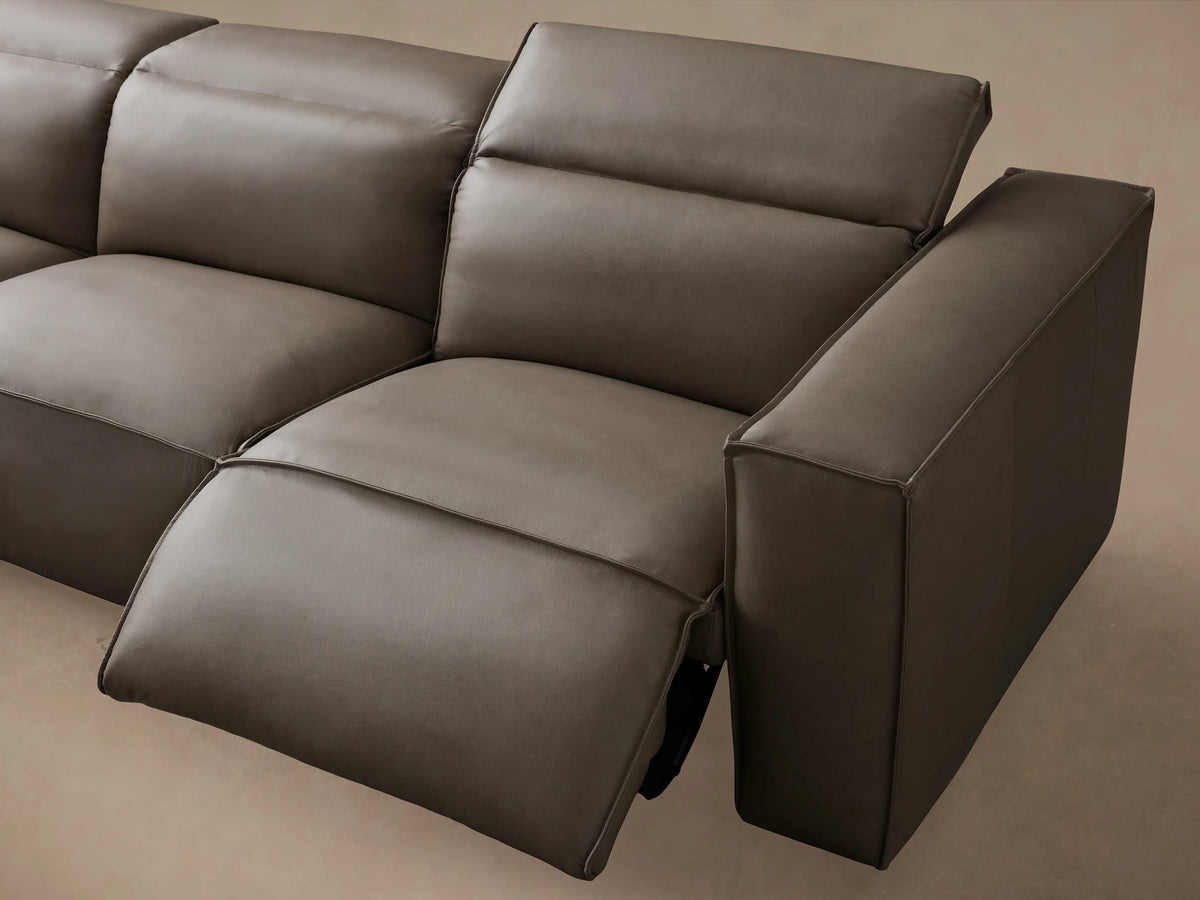 Coburn Leather Six Piece Motion Sectional in gray, featuring six seats with plush cushions. L-shaped design on wood floor against a beige wall.