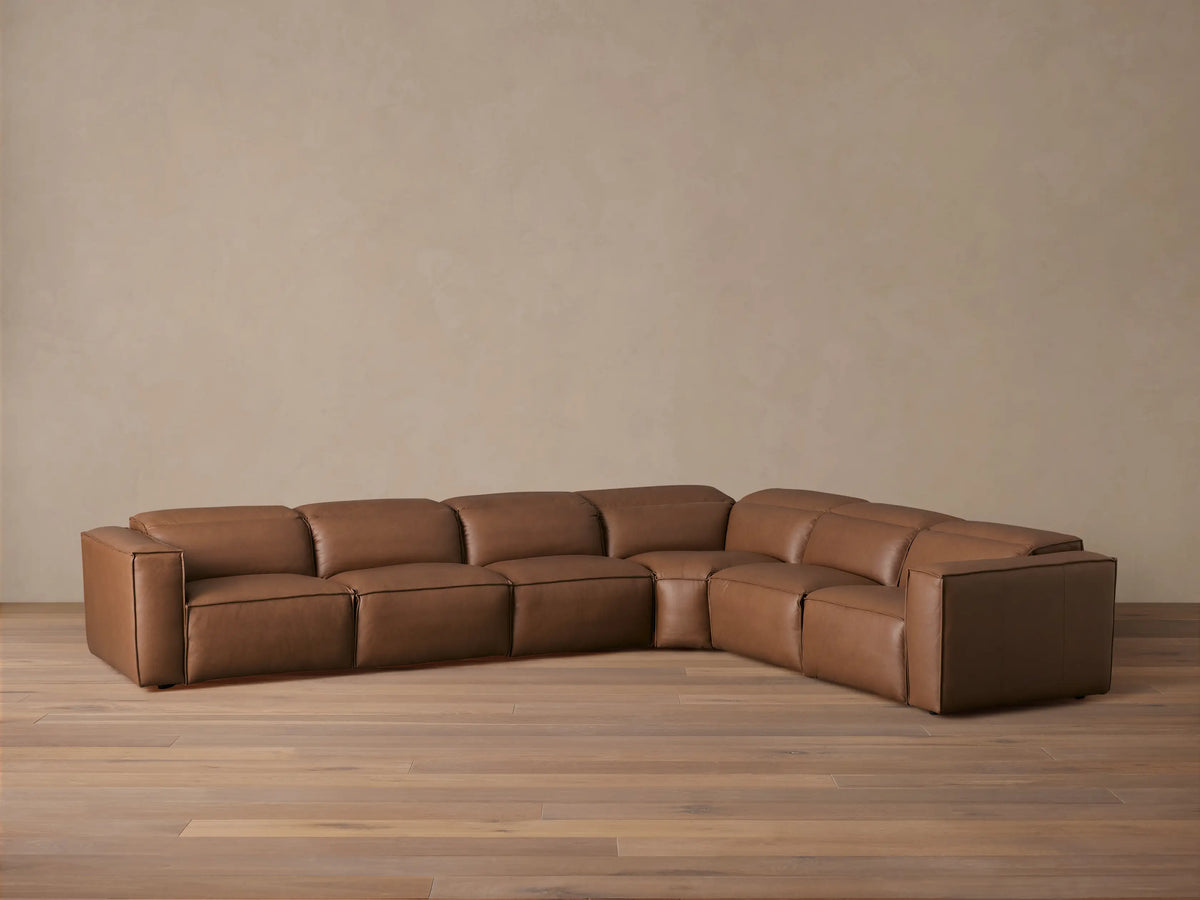 Brown leather six-piece Coburn sectional on a wooden floor. Includes left and right arm recliners and non-reclining corner. Backdrop is neutral.