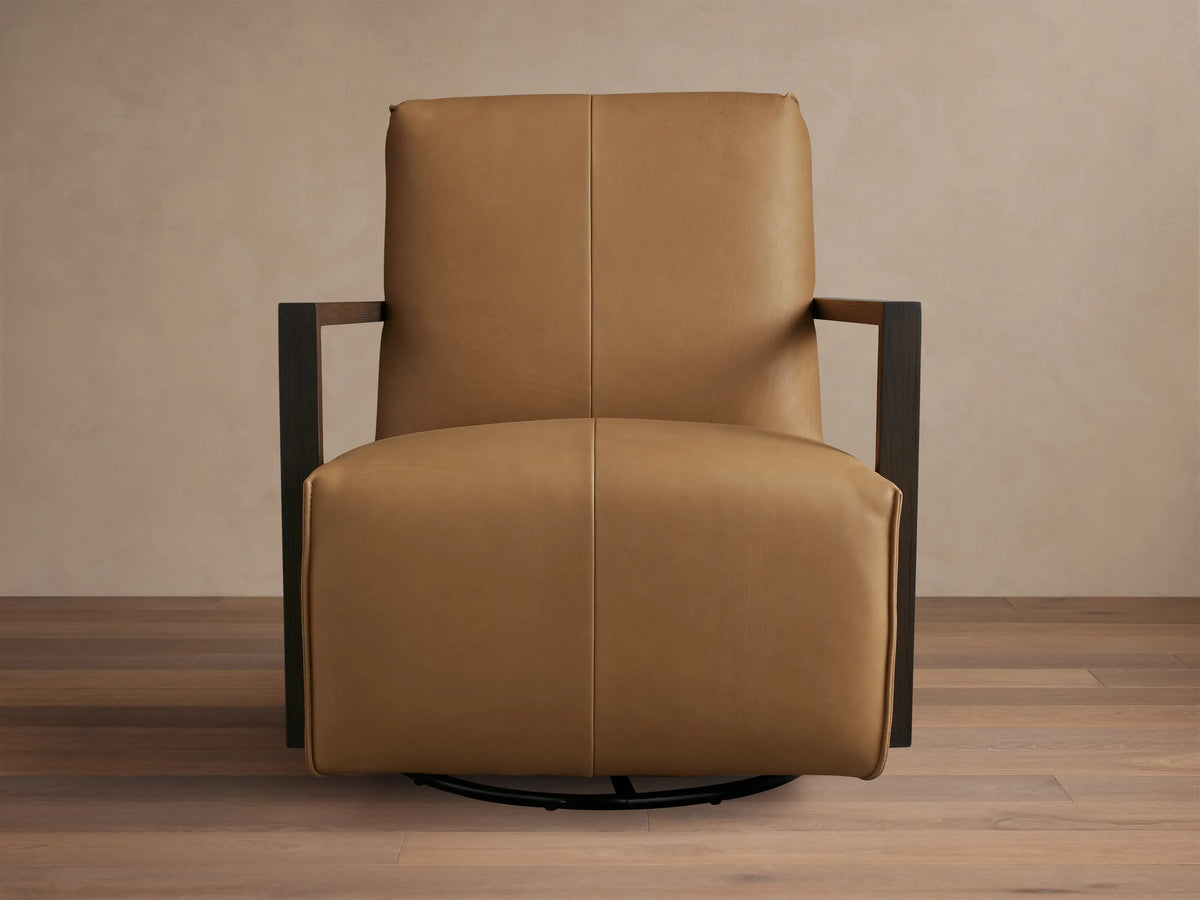 Modern Walsh Leather Glider in tan leather, with open dark wood armrests and black swivel base, angled on a wood floor.