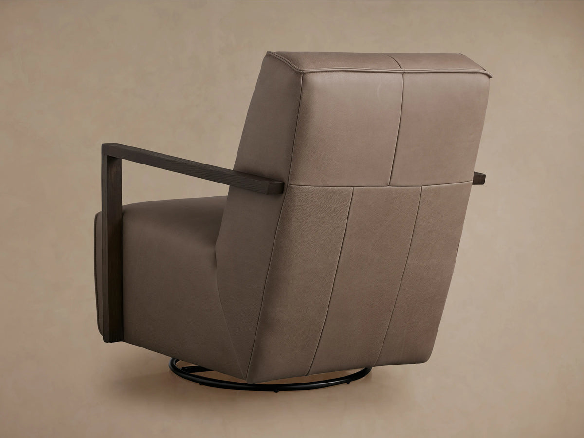 Front view of Walsh Leather Glider, light brown leather with dark wooden arms, on a black swivel base. Against a tan wall & wood floor.