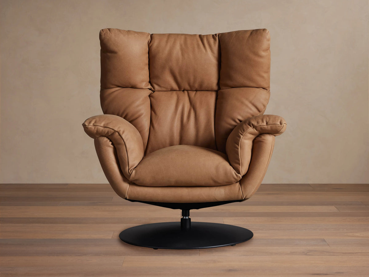 Tan Deacon Leather Swivel Recliner, front-angled, plush cushions, rolled arms, and a black circular swivel base on wood floor.