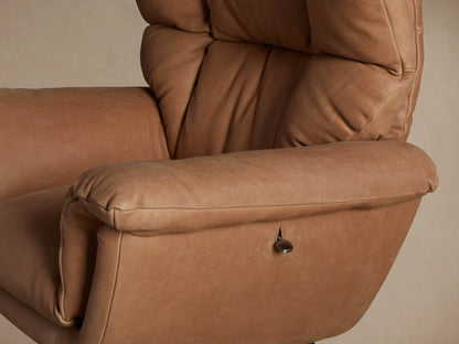 Tan leather Deacon Swivel Recliner with plush cushions & rolled arms, on a black round swivel base, against a neutral wall.