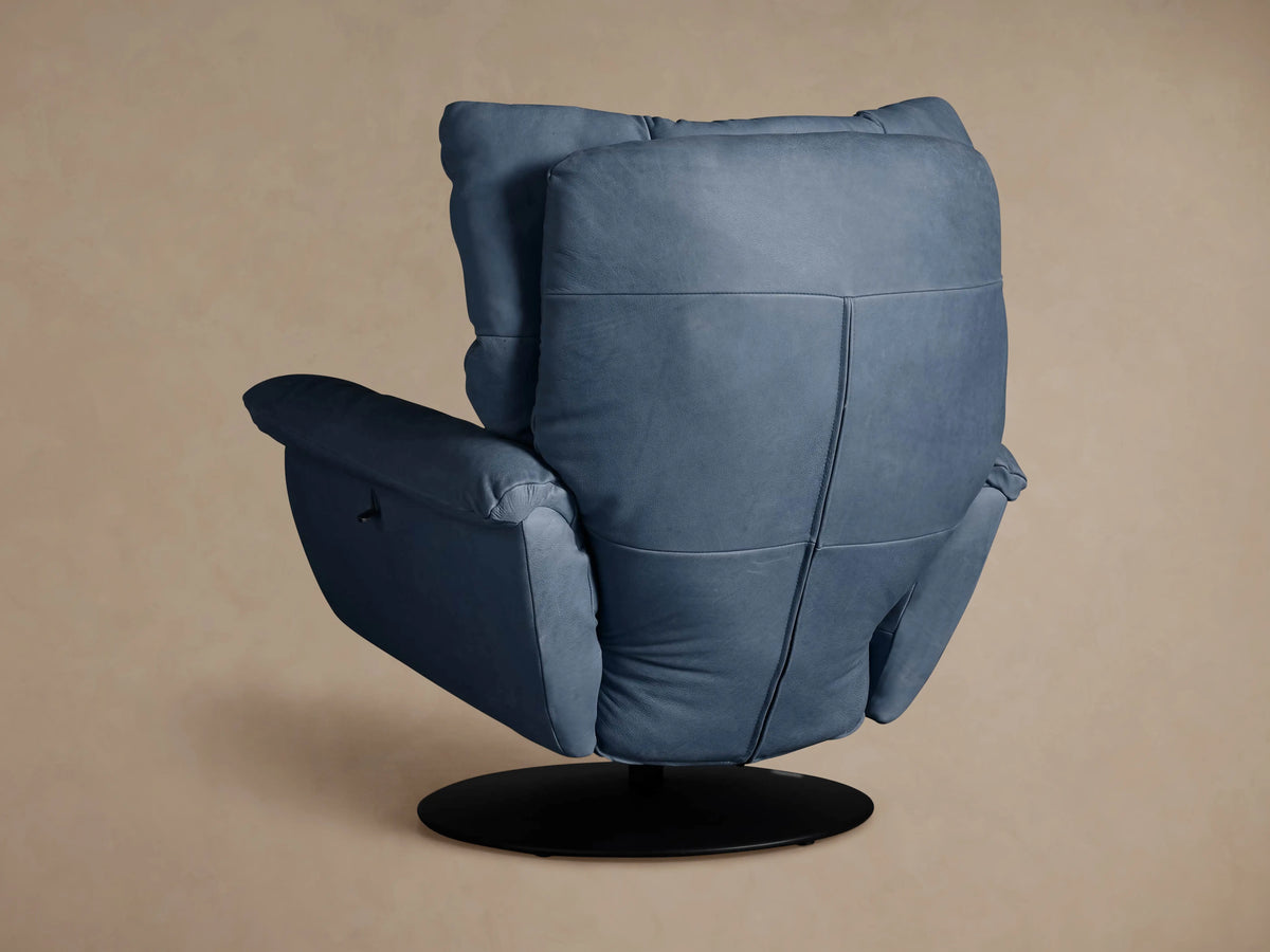 Angled view of blue leather Deacon Swivel Recliner, focusing on armrest with black reclining lever & cushioned back.