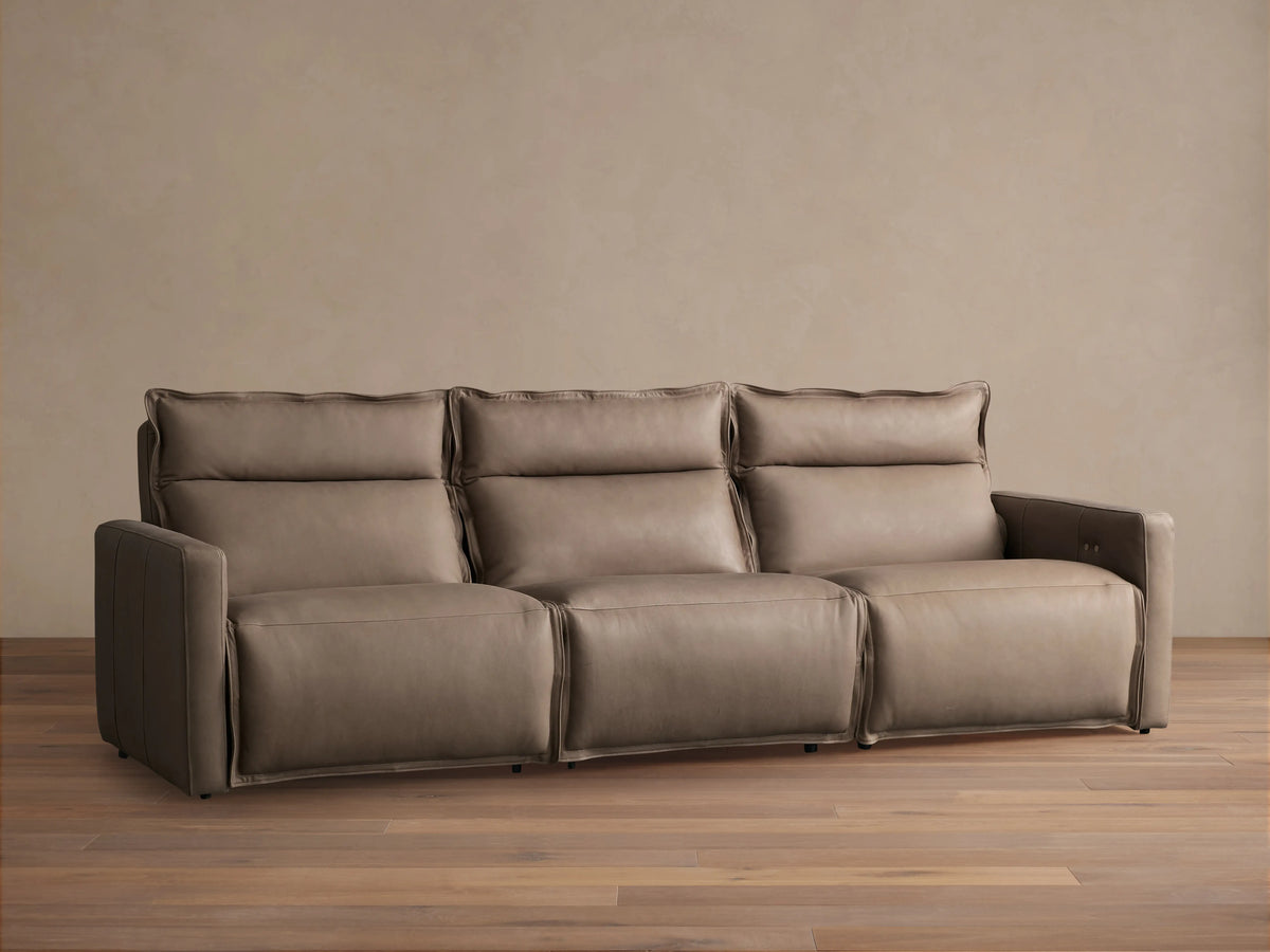 Rowland Leather Three-Piece Motion Modular Sofa in a neutral color, featuring three individual sections with cushioned backrests and armrests, on a wooden floor.
