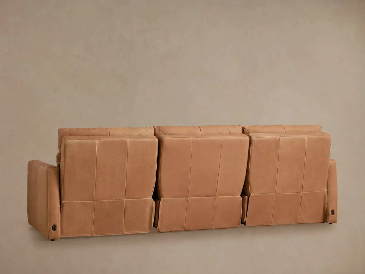 Close-up of a Rowland Tailored Leather Modular Sofa, showing its warm brown leather, tailored stitching, and armrest.