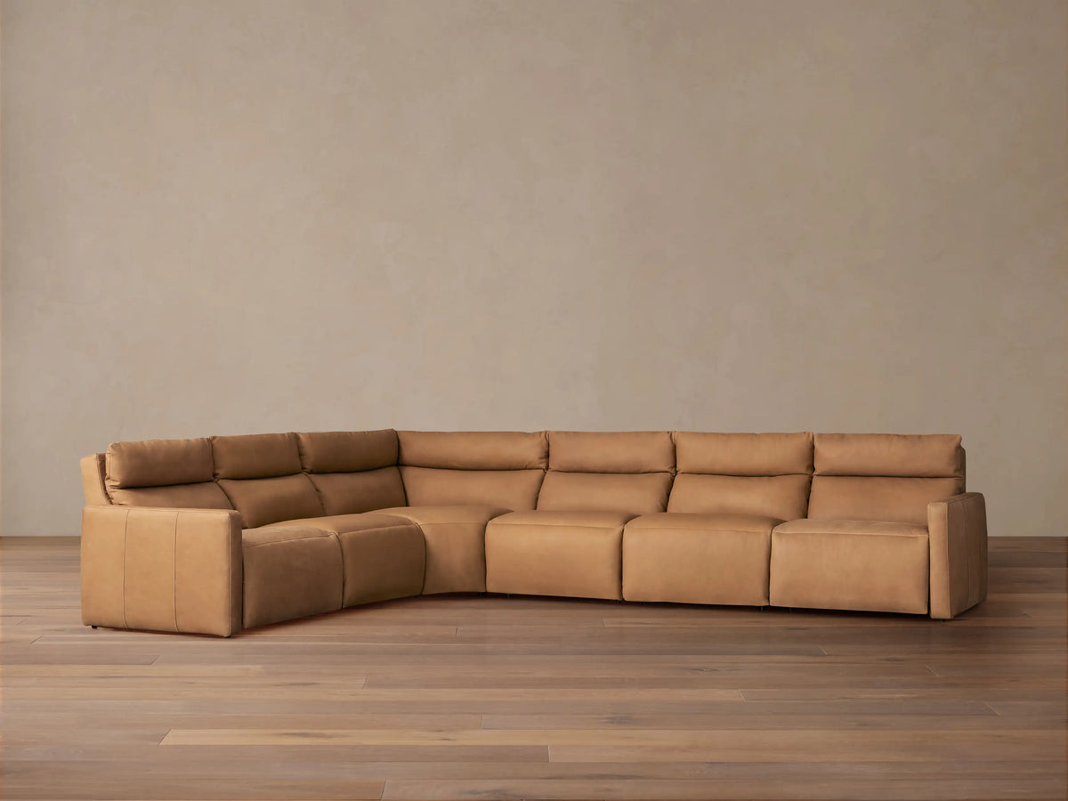 Back view of an L-shaped Rowland Tailored six-piece motion sectional in light brown leather against a plain neutral background.