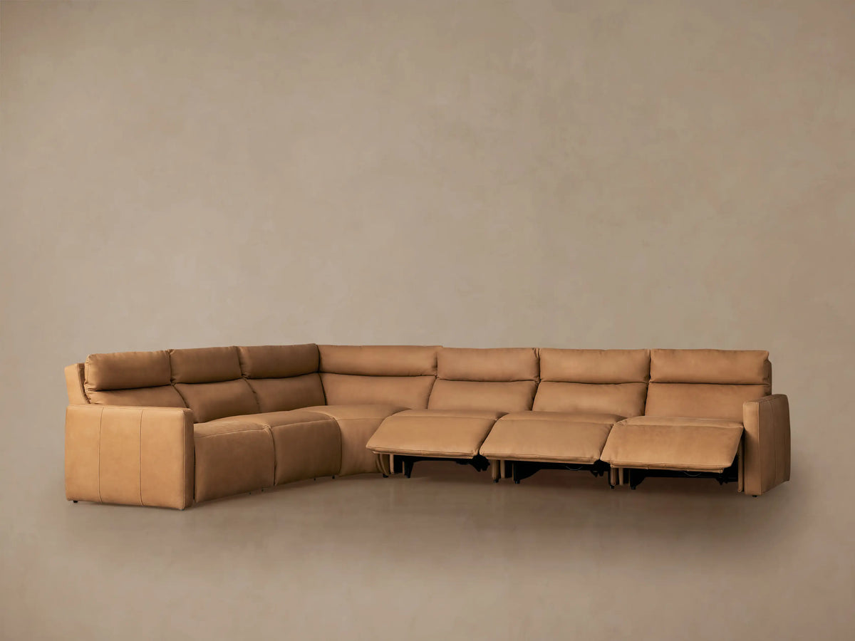 Rowland Tailored Six-Piece Motion Sectional, light tan leather, L-shaped, against a plain wall on a wood floor.