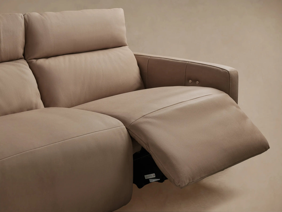 Close-up: Rowland Modular Sofa's tan leather backrest & seat with vertical stitch, featuring two silver motion control buttons.