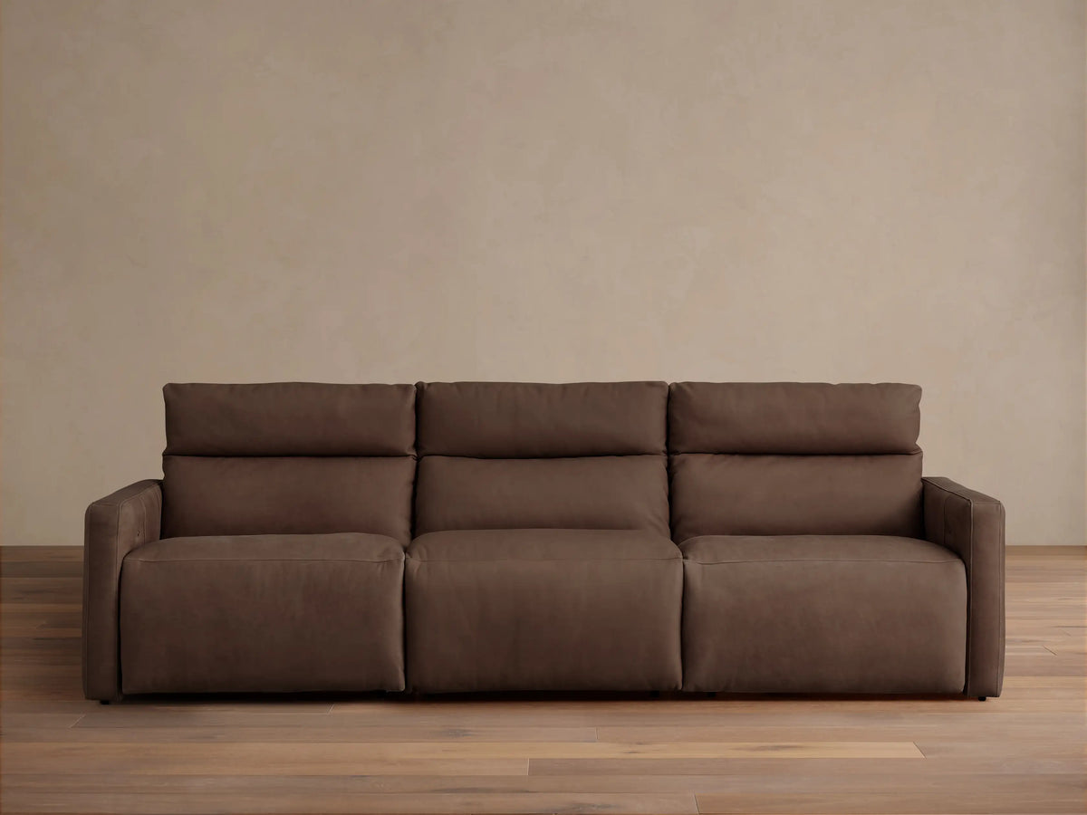 Dark brown tailored leather Rowland 3-piece motion modular sofa, front view, against a light beige wall and wood floor.