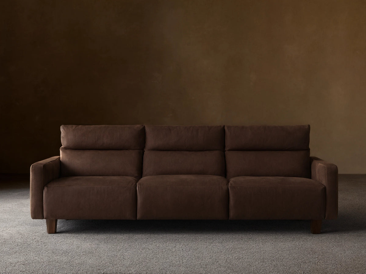 Dark brown tailored leather Rowland 3-piece motion modular sofa, front view, against a light beige wall and wood floor.