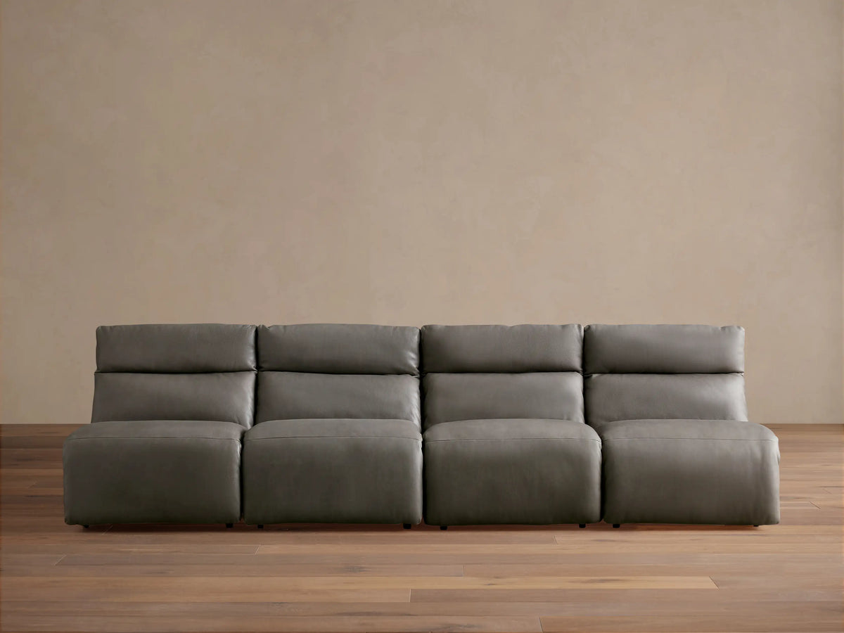 Rowland Tailored charcoal gray leather four-piece armless modular sofa on a wooden floor, against a light brown wall.