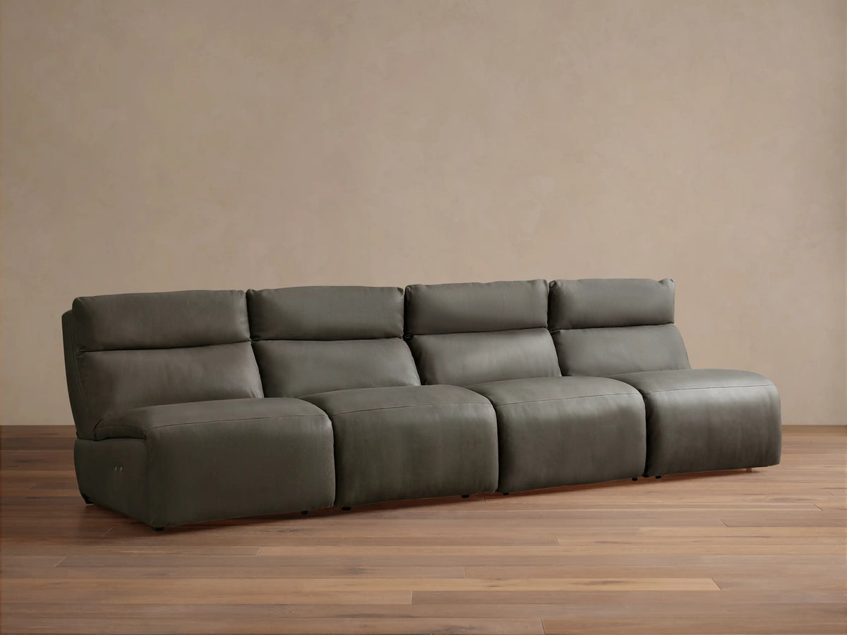 Rowland Tailored charcoal gray leather four-piece armless modular sofa on a wooden floor, against a light brown wall.