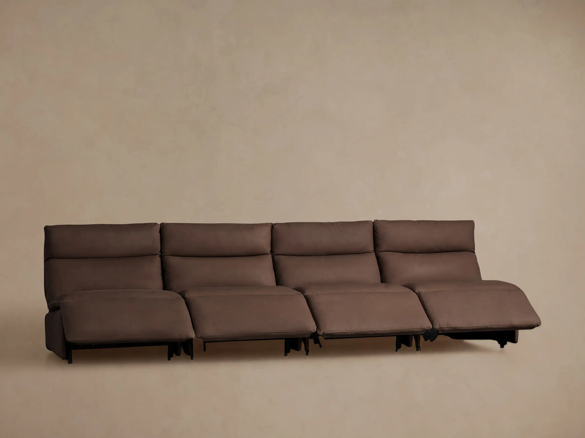 Rear view of a Rowland Tailored four-piece armless modular sofa in dark brown leather, against a light brown wall.