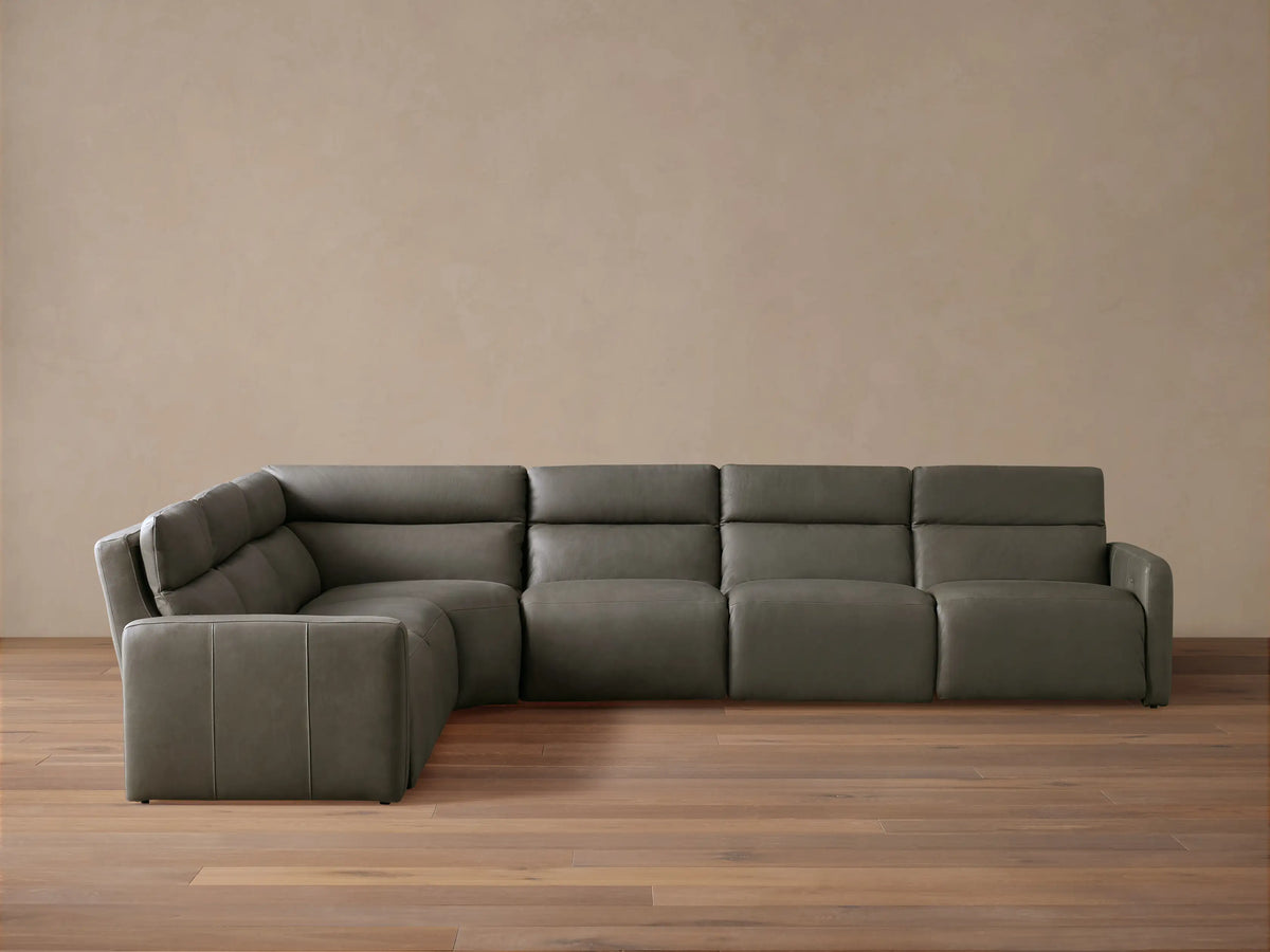 Dark gray Rowland Tailored Leather Six-Piece Motion Sectional, L-shaped, with clean, modern lines, on a hardwood floor.