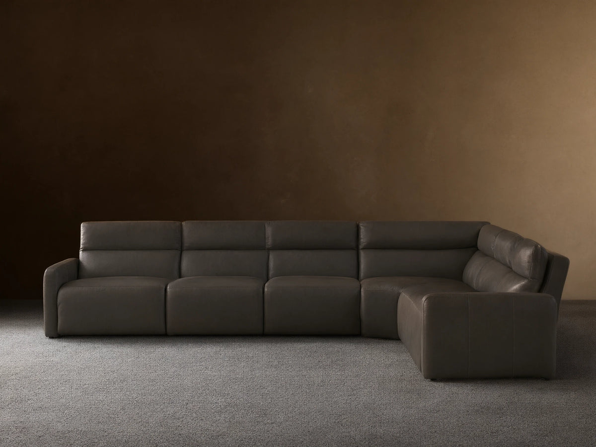 Dark gray Rowland Tailored Leather Six-Piece Motion Sectional, L-shaped, with clean, modern lines, on a hardwood floor.