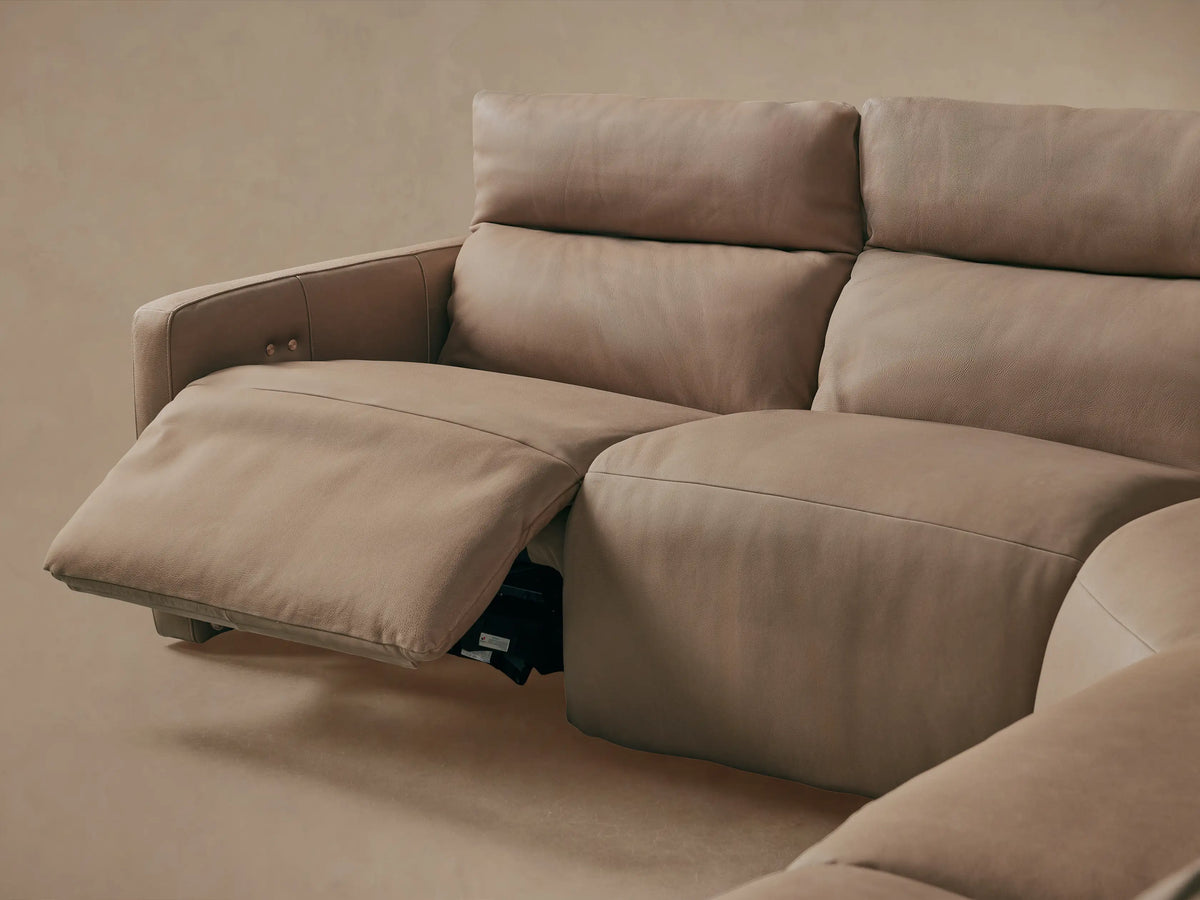 Close-up of Rowland Tailored Leather Sectional's brown textured leather back with two metallic buttons & stitching.