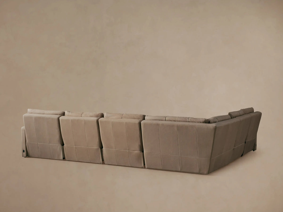 Close-up of a light beige leather Rowland Motion Sectional with one recliner footrest extended and backrest slightly reclined.