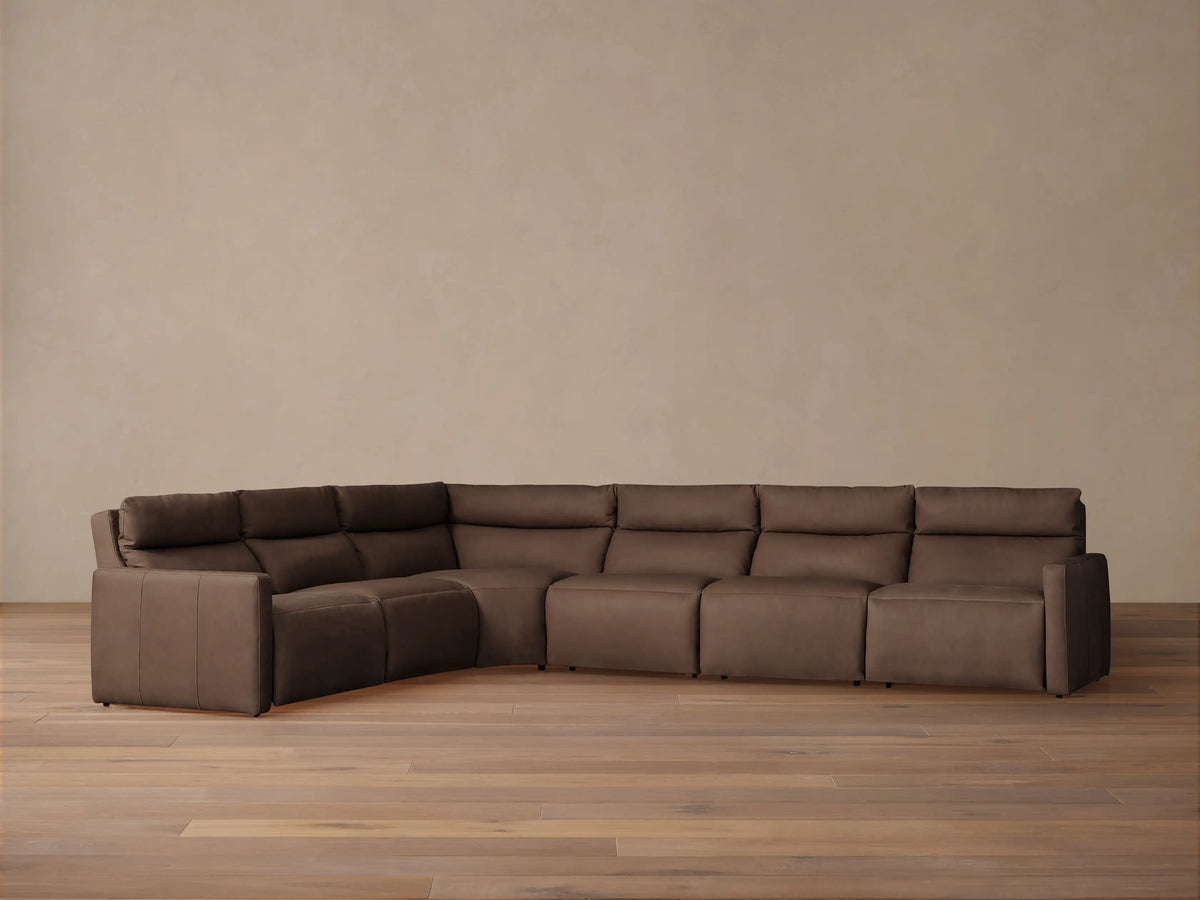 L-shaped Rowland Tailored Leather Six-Piece Motion Sectional in rich brown, on a light wood floor against a neutral wall.