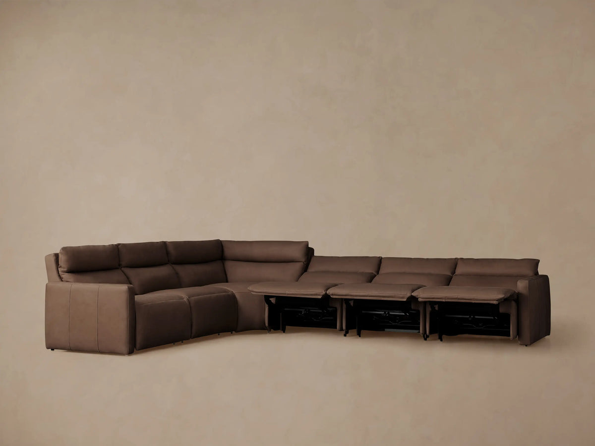 Rowland Tailored L-shaped leather motion sectional in dark brown, several footrests extended, against a plain wall.