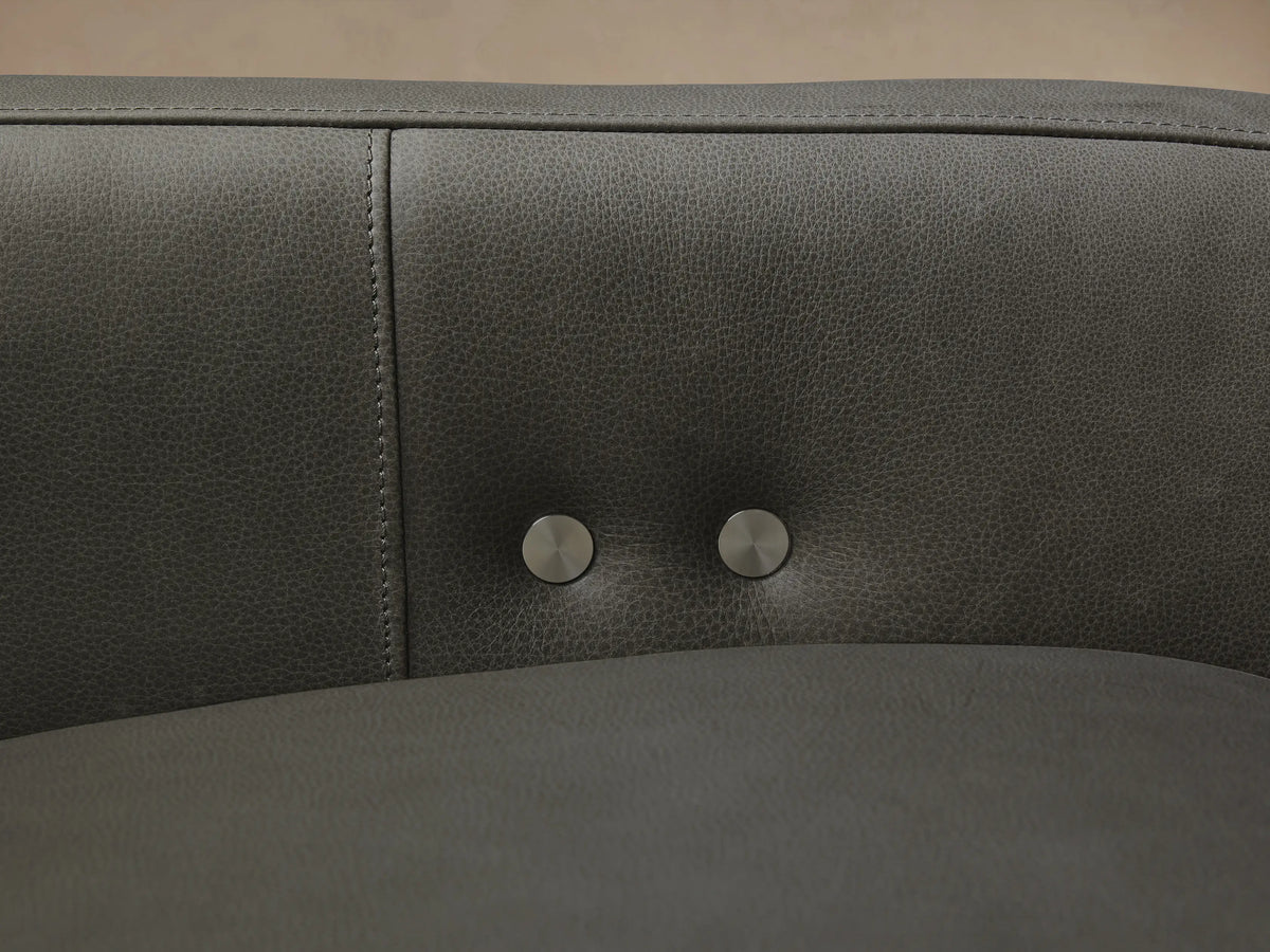 Rowland Tailored Leather Six-Piece Motion Sectional in dark charcoal grey, L-shaped, on a wood floor against a light wall.