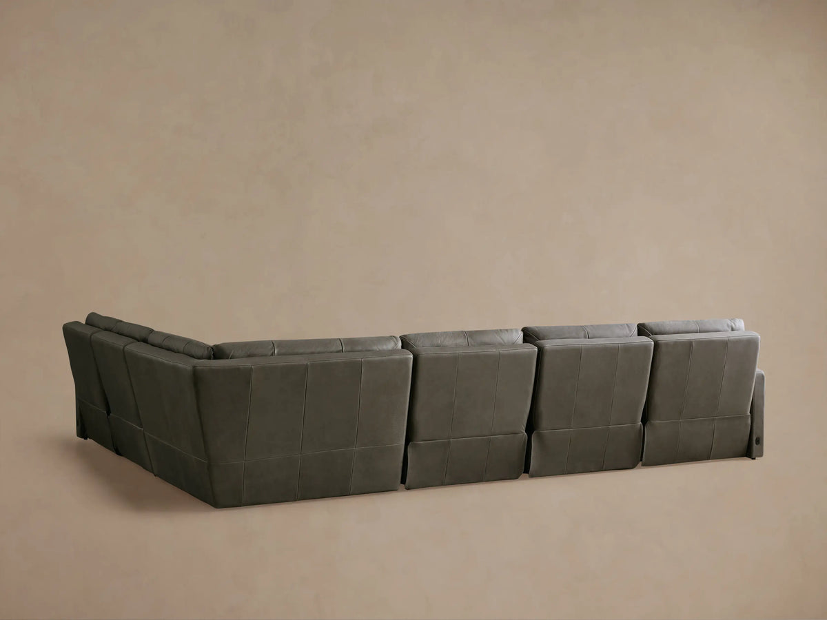 Dark grey Rowland Tailored Leather Motion Sectional with one recliner's footrest extended, showing its functionality.