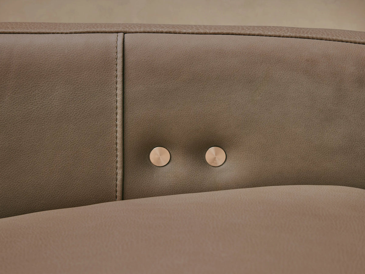 Light taupe Rowland Tailored Leather Six-Piece Motion Sectional, L-shaped, against a beige wall on a wooden floor.