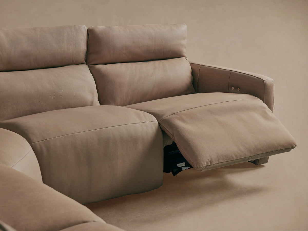 Close-up of Rowland Tailored Leather Motion Sectional's taupe leather backrest with vertical stitching and two bronze tufting buttons.