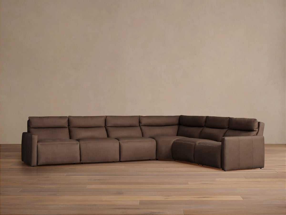 Rowland Tailored six-piece L-shaped motion sectional in dark brown leather, placed against a beige wall on a wood floor.
