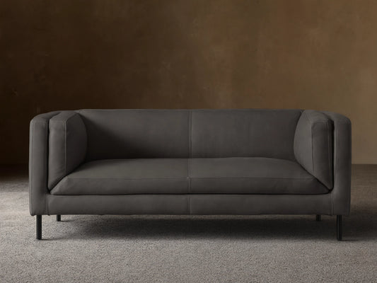 Front view of a modern dark grey Malta Leather Sofa with distinctive square arms, two seat cushions, and black recessed legs.