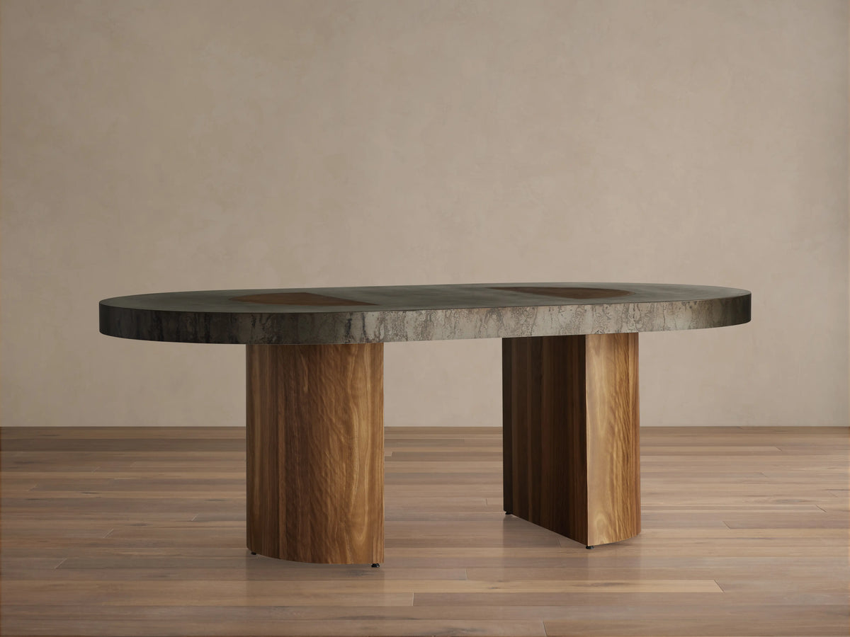 Oval Acacius Dining Table with a dark, smooth surface on two sturdy reclaimed wood legs; set in a neutral-toned room.