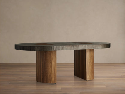 Oval Acacius Dining Table with a dark, smooth surface on two sturdy reclaimed wood legs; set in a neutral-toned room.
