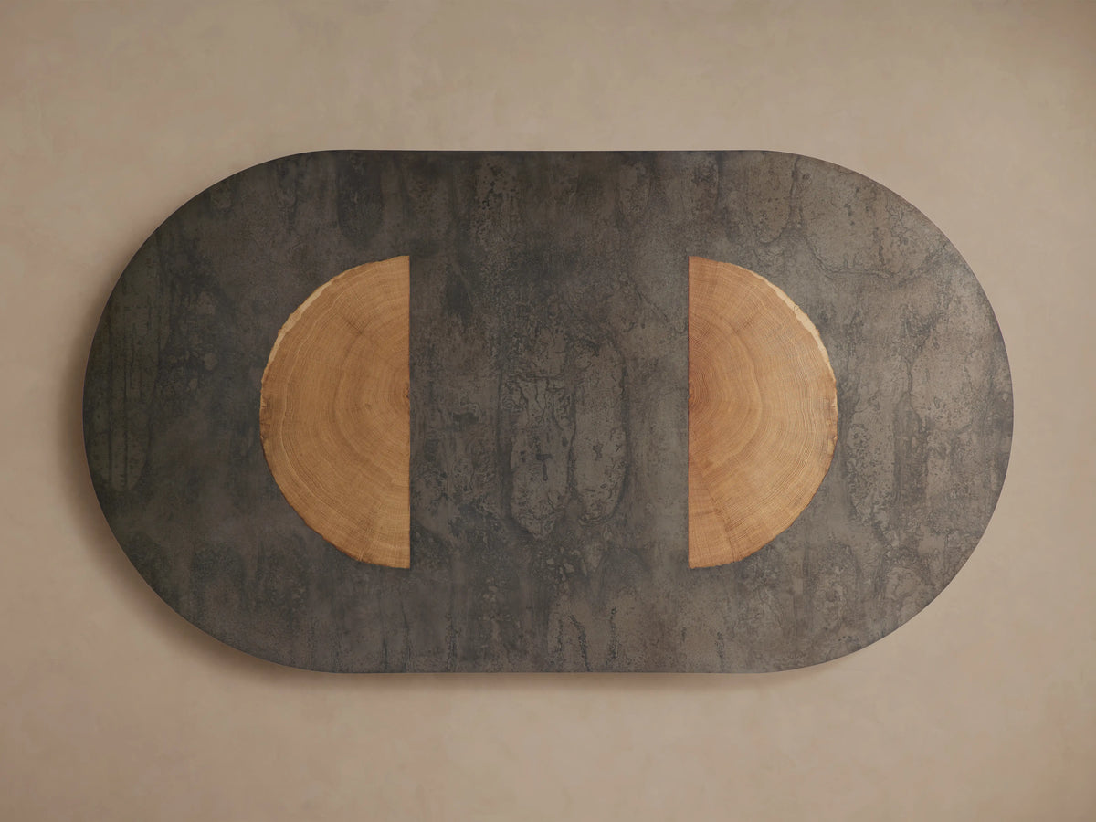 Oval Acacius Dining Table with a dark, naturally oxidized steel surface and a semi-circular reclaimed yukas veneer inlay.
