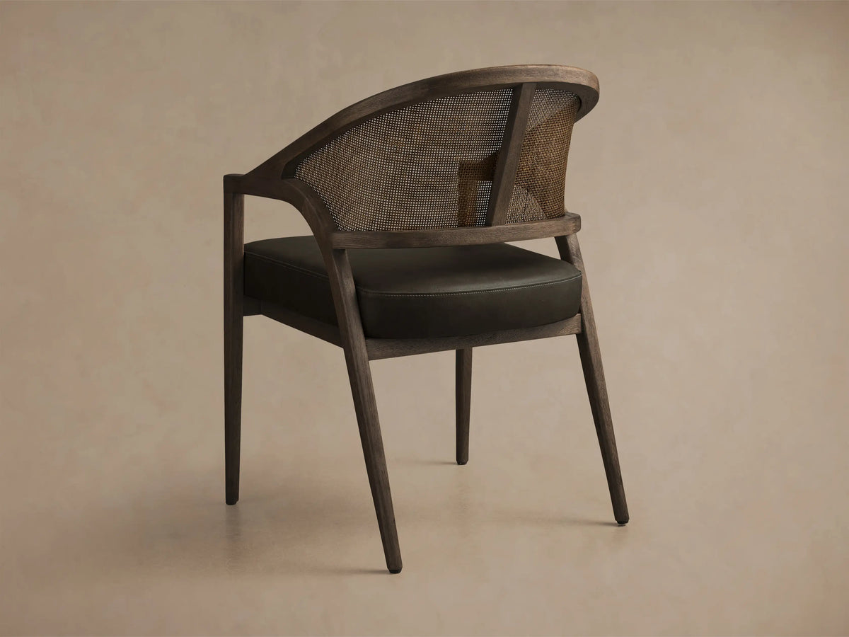 Front view of the Aimee Faux Leather Dining Arm Chair, featuring a dark oak frame, woven rattan back, and dark green faux leather seat.