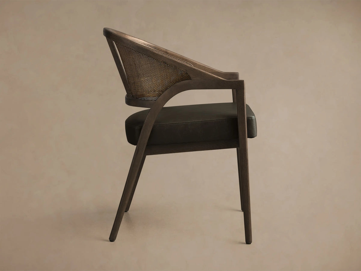 Front view of the Aimee Faux Leather Dining Arm Chair with a Black Drifted oak frame, natural rattan back, and dark faux leather seat.