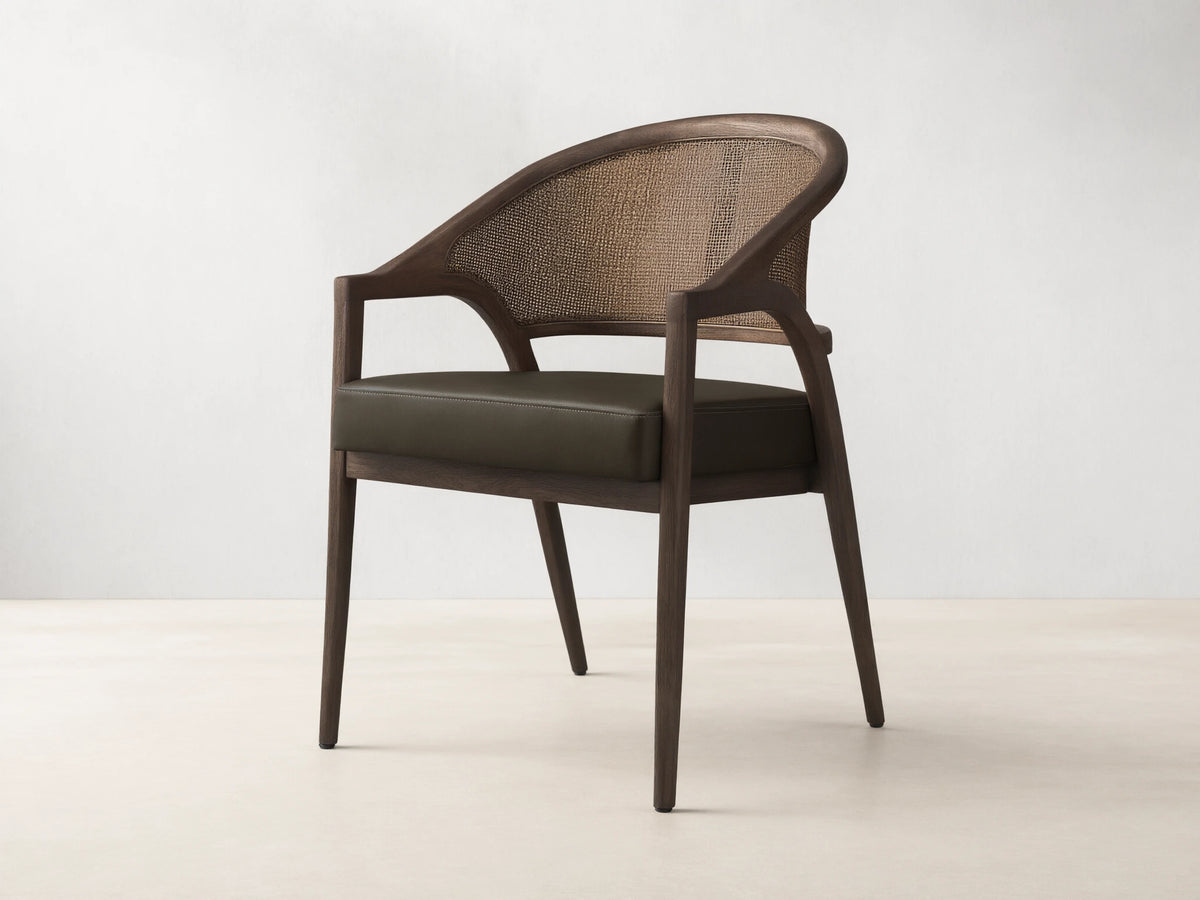 Front view of the Aimee Faux Leather Dining Arm Chair, featuring a dark oak frame, woven rattan back, and dark green faux leather seat.