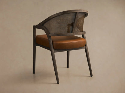 Rear view of the Aimee Faux Leather Dining Arm Chair with a black drifted solid oak frame, rattan cane back, and brown faux leather seat.
