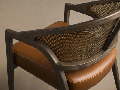 Side view of Aimee Faux Leather Dining Arm Chair with a dark wood frame, cane back, and brown faux leather seat.