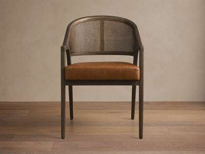 Close-up of the Black Drifted Aimee Faux Leather Dining Arm Chair with dark wood frame, brown rattan cane back, and brown faux leather seat.