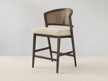 Aimee Armless Counter Stool with solid oak frame, rattan cane back, and upholstered seat. Hand-finished wood with lacquer.